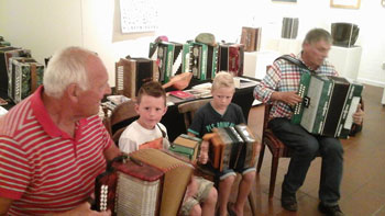 Age de Boer demonstreert zijn trekzak aan enkele kinderen. Op de achtergrond de Kaukasische trekzakken van Jan Hoog-Antink, die ook in actie is op een van zijn instrumenten.