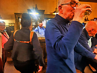 Jammen bij de bar. We zien hier de rug van Raquel Gigot, waarbij een dwarsverbindig de draagriemen van haar chromatische accordeon tot een soort tuigje maakt: vaak nood­zakelijk tegen het afzakken van met name de linker schouderriem.